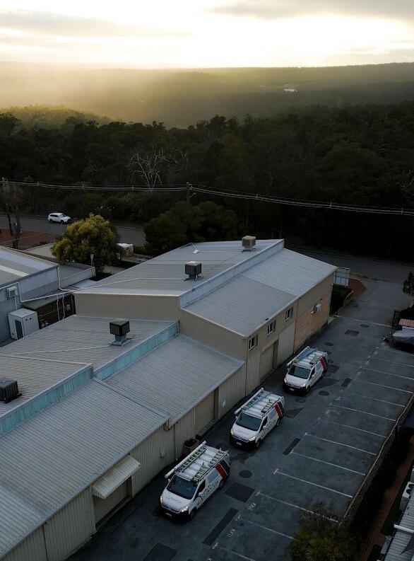 Aerial view of three Quantum Electrical vans parked at a commercial building in the Perth Hills